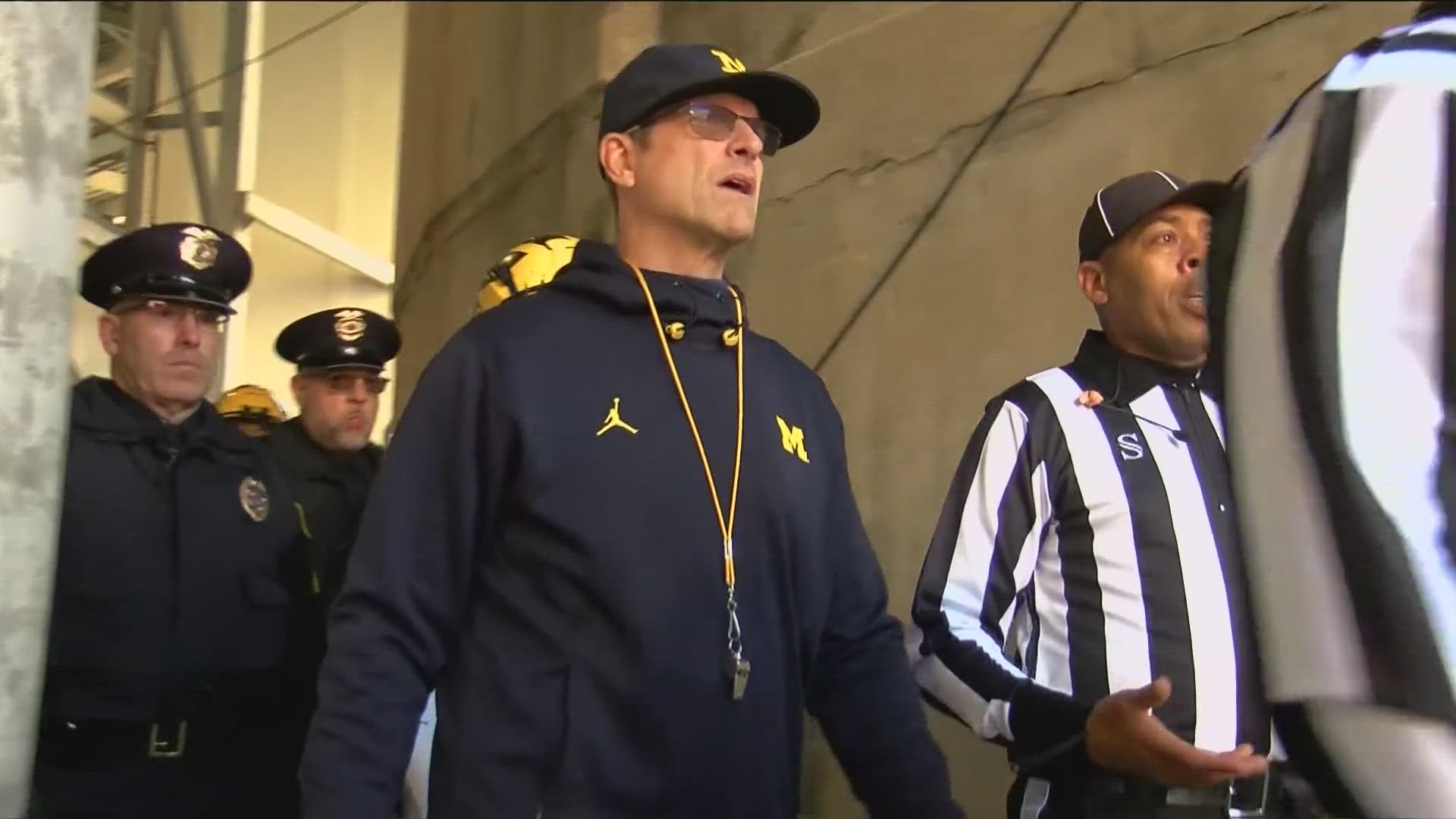 The school has asked a Michigan judge for a temporary restraining order that would allow Harbaugh to coach in the Wolverines' biggest game of the season.